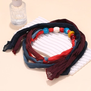 Detail of handcrafted tie-dye fabric strips and colorful glazed glass beads on necklace
