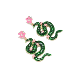 Macro detail of snake drop earrings with green enamel and pink rhinestone flowers