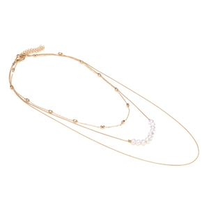 Collana dorata a tre strati con perle finte e sfere di metallo lucido su sfondo bianco