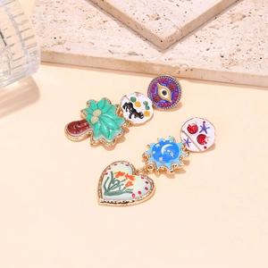 Close-up of asymmetric enamel earrings with colorful eye, palm tree, and heart charms