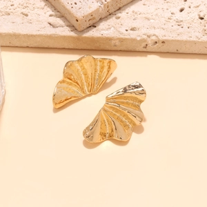Close-up of golden fan-shaped leaf earrings with vintage textured metal finish