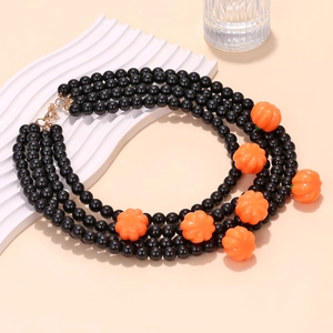 Three-layer Halloween pumpkin pendant necklace with black handmade beads on a white tray