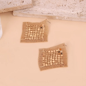 Dettaglio macro di orecchini geometrici dorati con frange metalliche esagonali