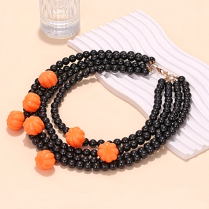 Close-up of multilayered black beads and orange pumpkin charms for Halloween necklace