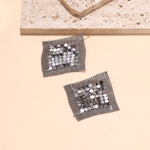 Dettaglio di orecchini geometrici quadrati con paillettes argento e maglia metallica scura