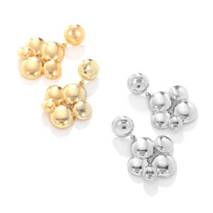 Detail of stacked irregular metallic spherical pendant earrings in gold and silver finish