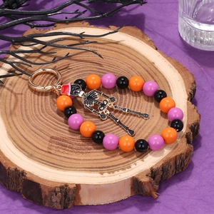 Halloween keychain featuring a skull charm with colorful orange and purple beads on wood
