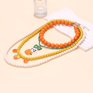 Three-layer Halloween beaded necklace featuring pumpkin and BOO charms on beige background