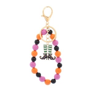 Close-up of Halloween keychain with colorful beads and enameled witch leg charm detail