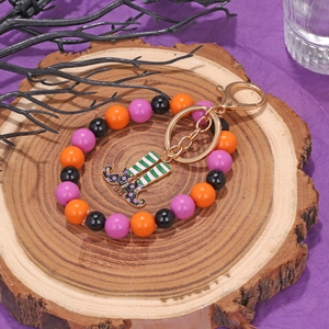 Detail of Halloween keychain with witch boot charm and colorful resin beads on wood