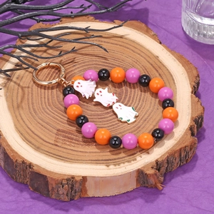 Detail of Halloween ghost keychain with orange, purple and black beads on wood base
