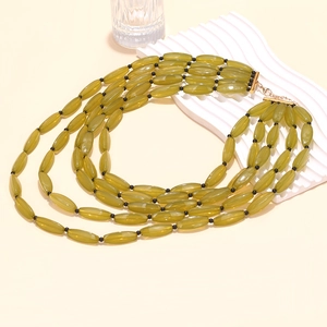 Multilayer olive green bead necklace with golden lobster clasp on a beige background