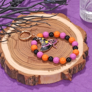 Detail of Halloween beaded keychain with purple witch hat charm on wooden stand