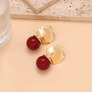 Detailed view of vintage gold geometric earrings with textured metal and deep red resin beads