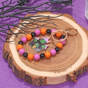 Detailed view of Halloween beaded keychain with haunted house pendant on rustic wood