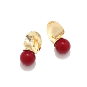 Detail of hammered gold metal texture and glossy red resin beads on geometric earrings