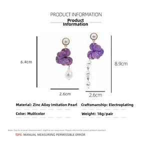 Detailed view of asymmetric earrings with purple enamel flowers and baroque pearls