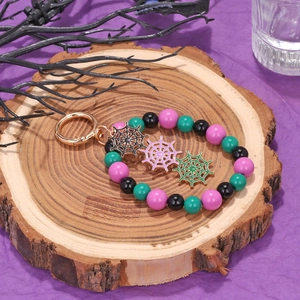 Halloween beaded keychain with colorful oil-drop spider web pendants on a wooden stand