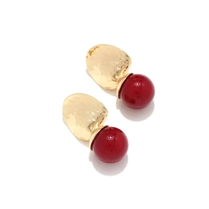 Detail view of irregular gold metal texture and bright red resin bead on these earrings