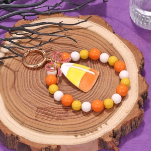 Beaded Halloween keychain featuring a candy corn charm on a rustic wood background