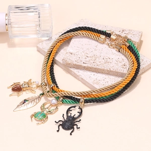 Détail de colliers en corde tressée colorée avec pendentifs scarabée et feuille d'or