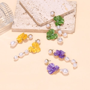 Detail view of colorful enamel flower earrings with baroque pearls in yellow, green and purple