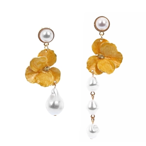 Close-up of asymmetric earrings with yellow enamel flowers and baroque white pearls