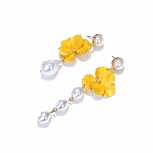 Detailed close-up of asymmetric yellow enamel flower earrings with Baroque pearl drops