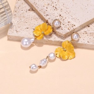 Detail of asymmetrical baroque pearl earrings with yellow enamel flower accents