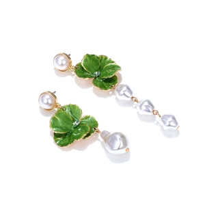 Detailed close-up of asymmetric floral earrings with green enamel and baroque pearls