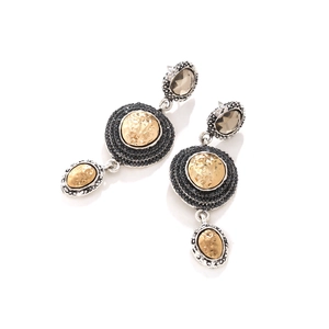 Close-up of vintage geometric earrings with faceted stones and hammered gold discs