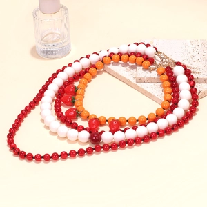 Detail of multi-layer beaded necklace featuring colorful beads and strawberry charms