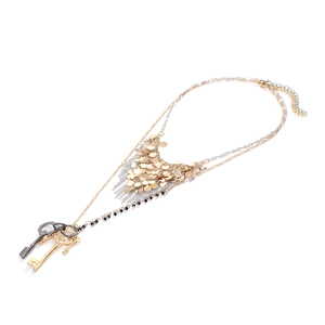 Collier multi-rangs en métal avec paillettes brillantes et pendentifs clés sur fond blanc