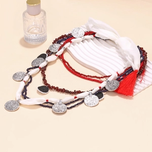 Detail of bohemian multi-layer beaded necklace with silver charms and a red tassel