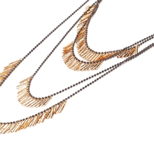 Détail d'un collier multicouche de style industriel avec des franges dorées et des perles
