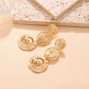 Elegant gold spiral triple hoop long earrings with textured finish on stone background