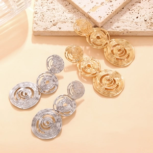 Detailed close-up of gold and silver triple concentric spiral textured hoop earrings