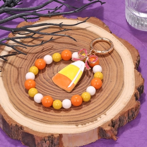 Halloween beaded keychain with candy corn pendant and pink bow on a wooden display