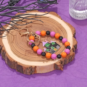 Halloween keychain with purple and orange beads and haunted castle pendant on wood background
