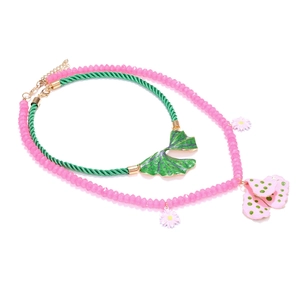 Layered floral pendant necklace with pink beads and green woven cord on white background
