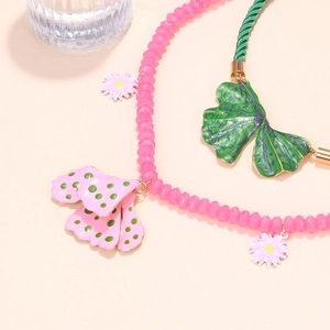 Detail of layered necklace with colorful resin beads, floral charms and enamel leaves