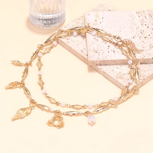 Detail of layered gold ocean necklace with fish crab charms and white pearls