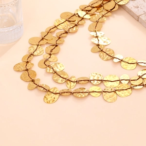 Detail of bohemian multilayer necklace with hammered gold disks and woven cord