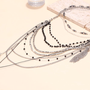 Macro detail of multi-strand silver necklace with black beads and waterfall metal tassels