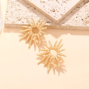 Golden sunflower drop earrings with textured metal finish on a stone background