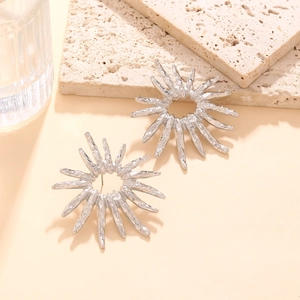 Macro detail of textured silver sunflower earrings with artistic sunburst starburst design