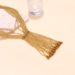Luxurious multi-layer gold beaded fringe necklace with long tassels on stone pedestal