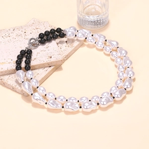 Detail of layered baroque pearl necklace featuring black beads and silver toggle clasp