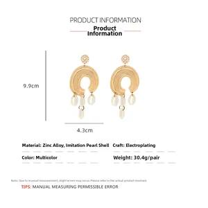 Detail shot of bohemian gold earrings with pearl flowers and shell tassels with dimensions