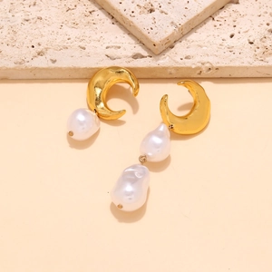 Asymmetric gold crescent moon earrings with baroque pearls on a textured stone display